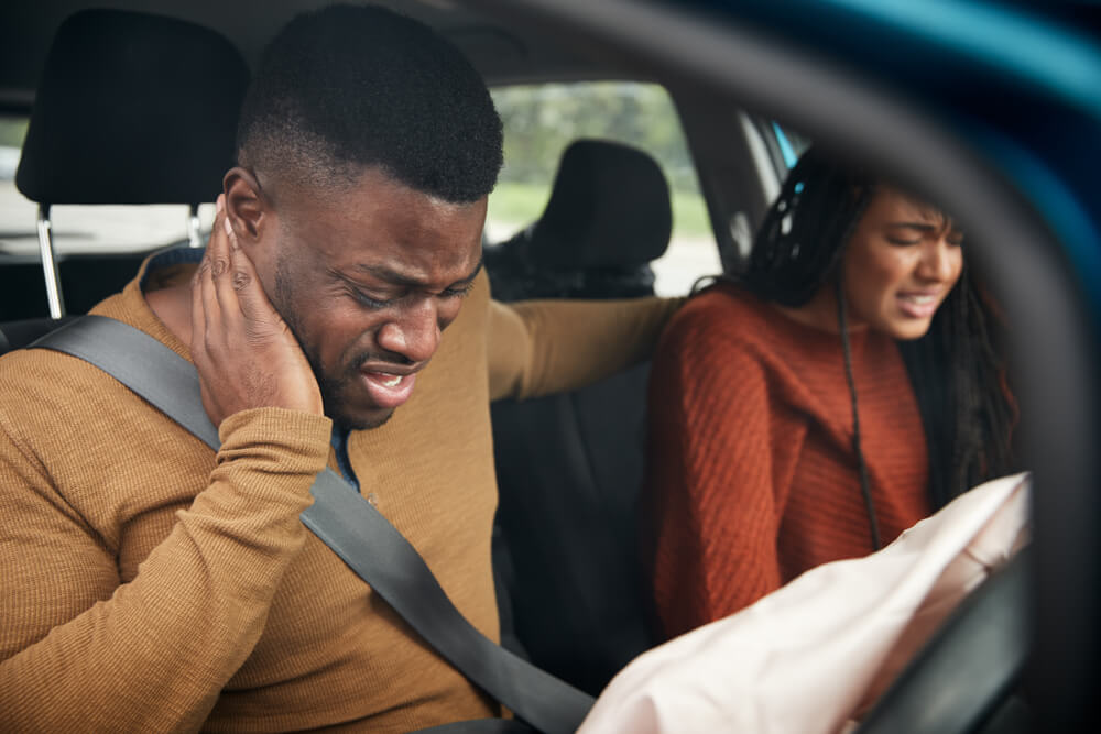 Injured car accident passengers in Texas holding injuries inside a vehicle after a crash, highlighting passenger rights to compensation