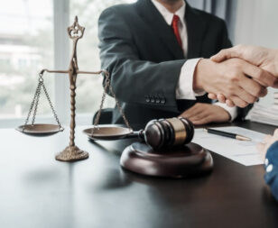 Client shaking hands with a Texas personal injury lawyer during a consultation with legal documents, gavel, and justice scales on the desk