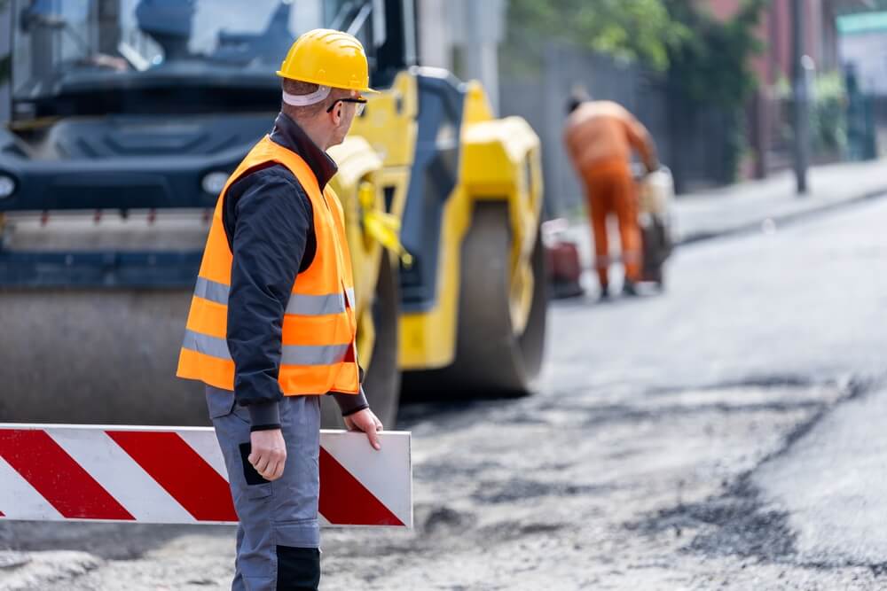 Construction worker setting up a barrier in a Texas road work zone, highlighting the dangers of work zone accidents and the need for safe driving.