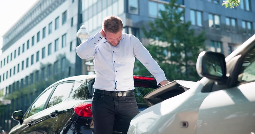Injured driver holding his neck after a Texas car accident, illustrating pain and suffering damages.